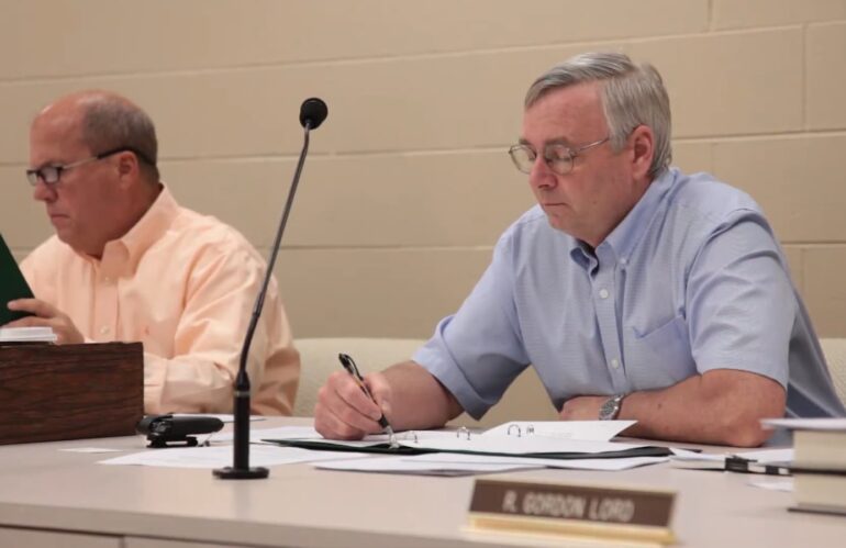 The man in glasses attentively reviews documents at a meeting